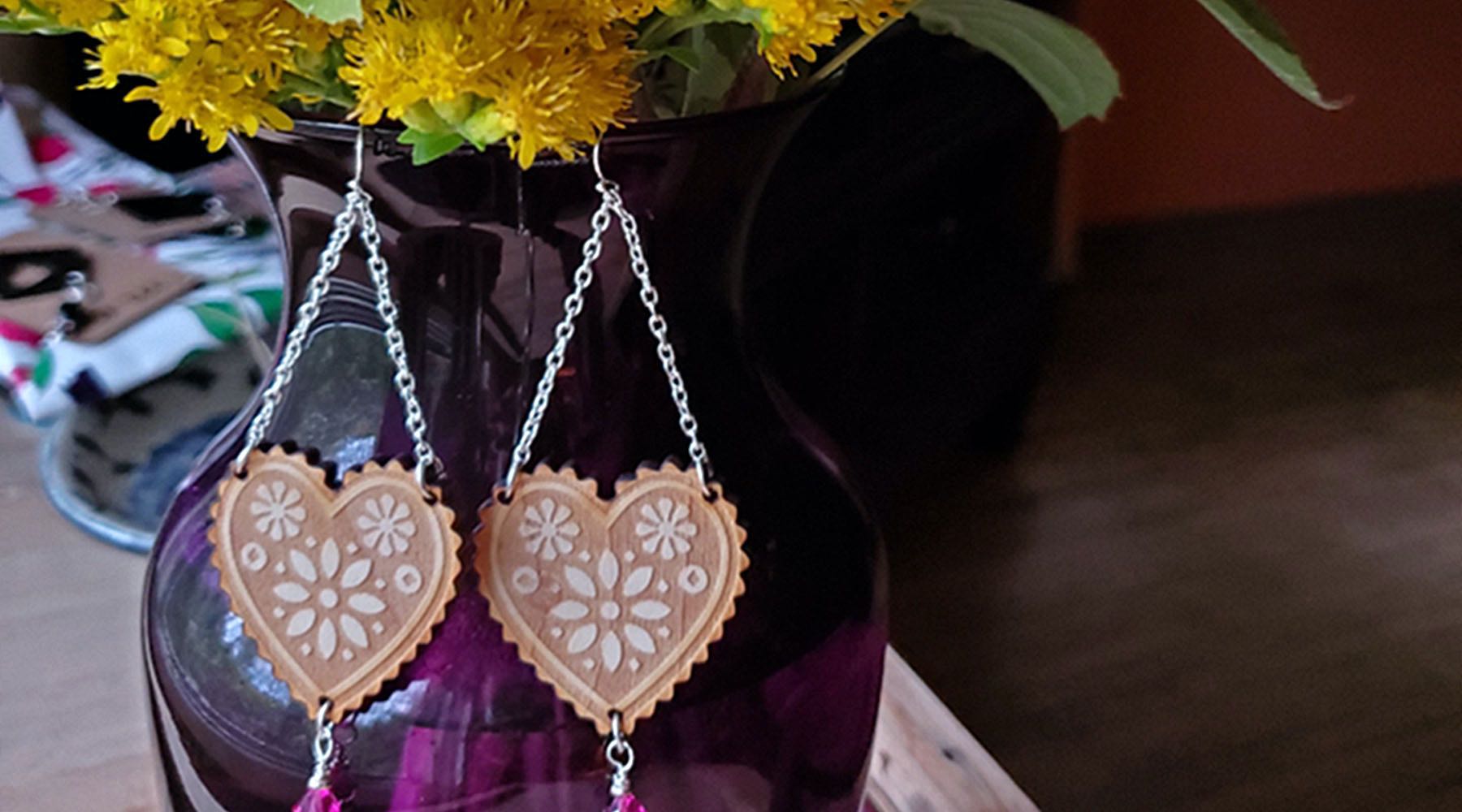 A pair of our beautiful custom made Folkloric earrings made from laser cut and engraved maple sith Stirling findings and a Swarovski crystal drop displayed on a vase with spring flowers. Were always working on new handcrafted goods. 